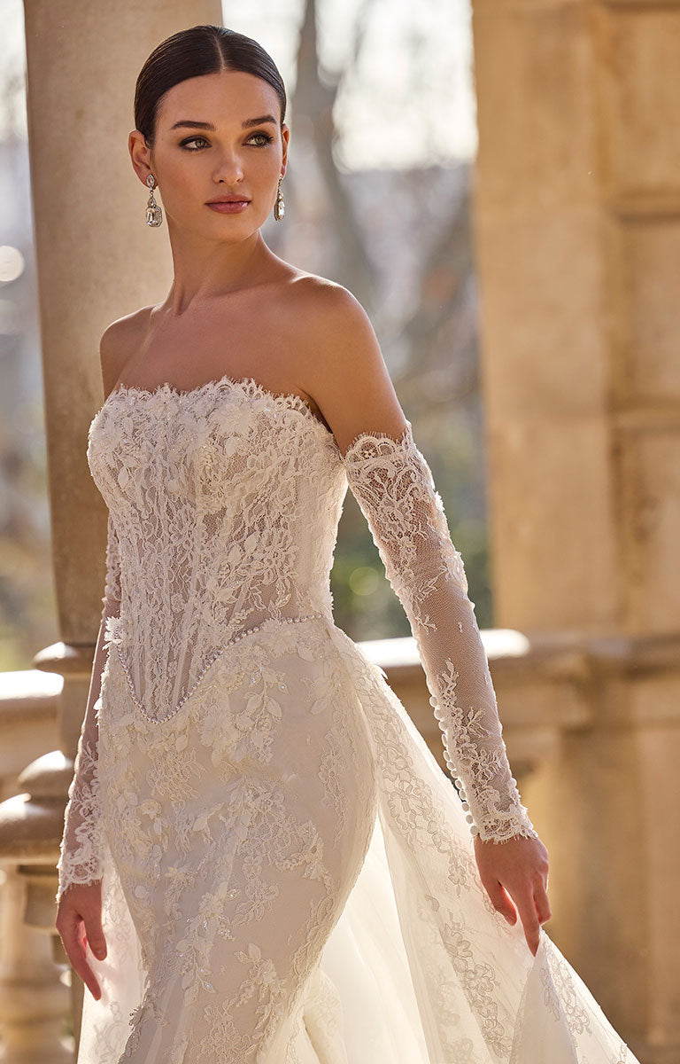 Woman wearing 63115A Hildred by Veni Infantino - Lace Wedding Dress with Romantic Silhouette with long sleeves in an outdoor setting.