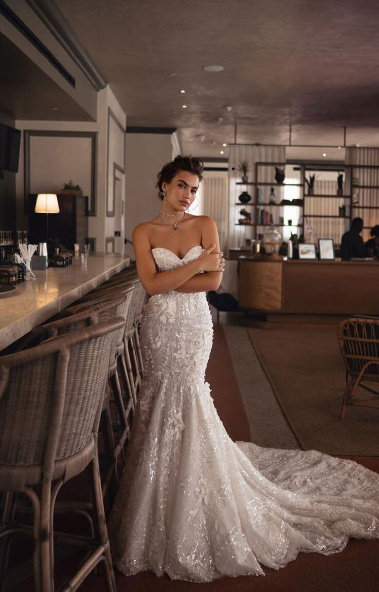 Woman in a white wedding dress standing in a modern indoor setting.