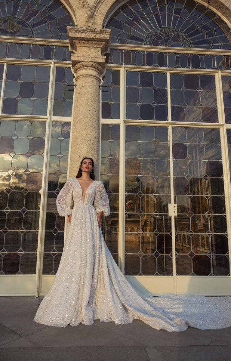 Woman in a white wedding dress standing in front of large stained glass windows.